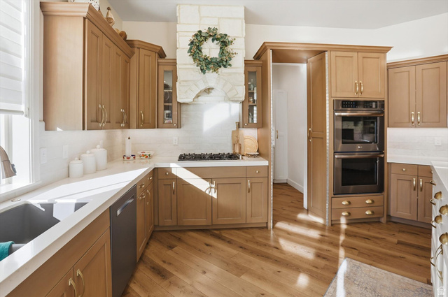 534 East Fish Hatchery Road Mantua, UT 84324 - Photo 24 of 87 Kitchen with light wood-style flooring, stainless steel appliances, backsplash, glass insert cabinets, and light stone countertops