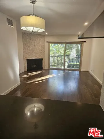 a view of an empty room with wooden floor and a floor to ceiling window