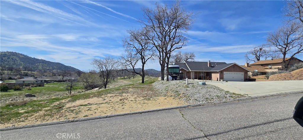 17701 Bold Venture Drive Tehachapi, CA 93561 - Photo 5 of 7 a view of a white house next to a road with large trees