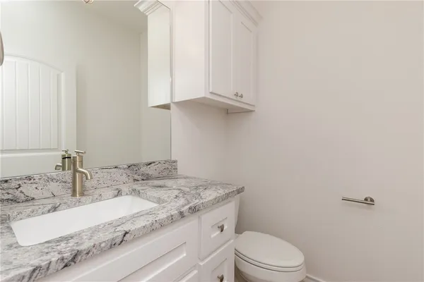 a bathroom with a granite countertop sink a toilet and a mirror