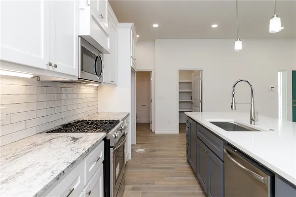 a kitchen with stainless steel appliances granite countertop a sink stove and cabinets