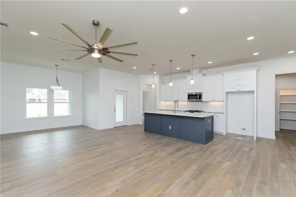 a large kitchen with stainless steel appliances granite countertop a large counter top a sink and a refrigerator