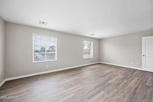 an empty room with wooden floor and windows