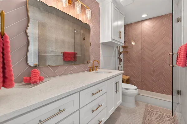 a bathroom with a granite countertop sink a toilet and shower