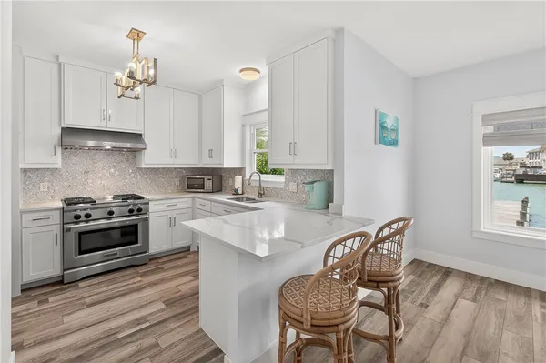 a kitchen with granite countertop a stove a sink dishwasher a dining table and chairs with wooden floor