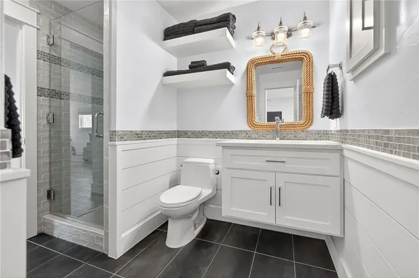 a bathroom with a toilet sink a mirror and shower