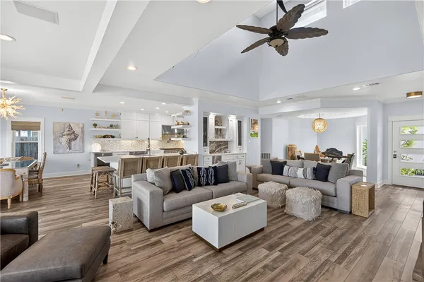 a living room with furniture kitchen view and a wooden floor