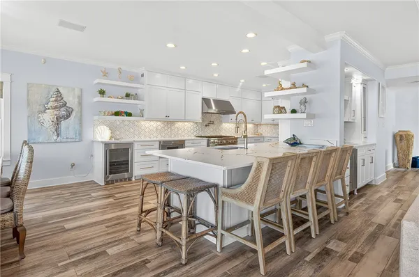 a kitchen with stainless steel appliances kitchen island granite countertop a dining table chairs and white cabinets