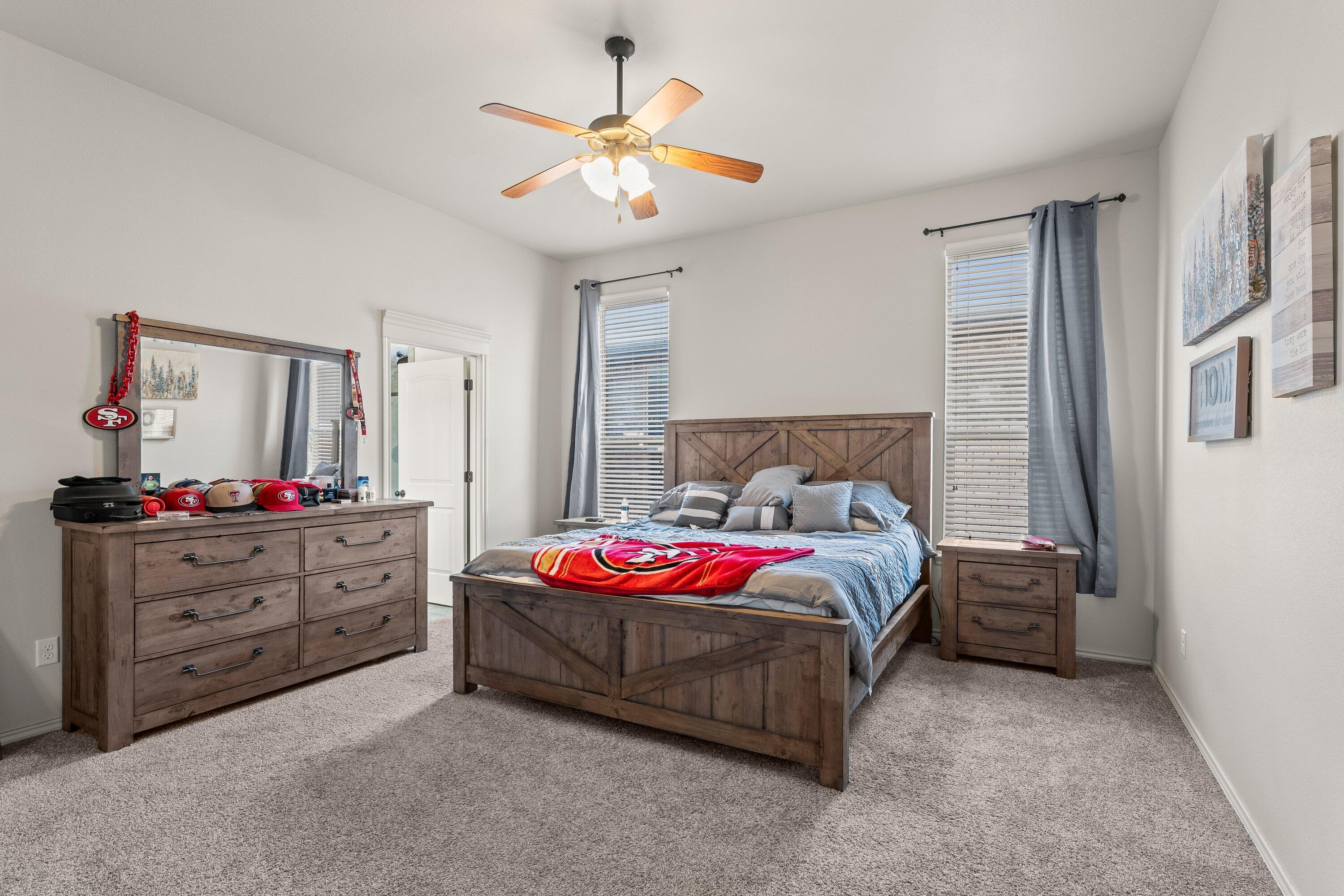 6305 93rd Street Lubbock, TX 79424 - Photo 14 of 31 a spacious bedroom with a bed and a chandelier