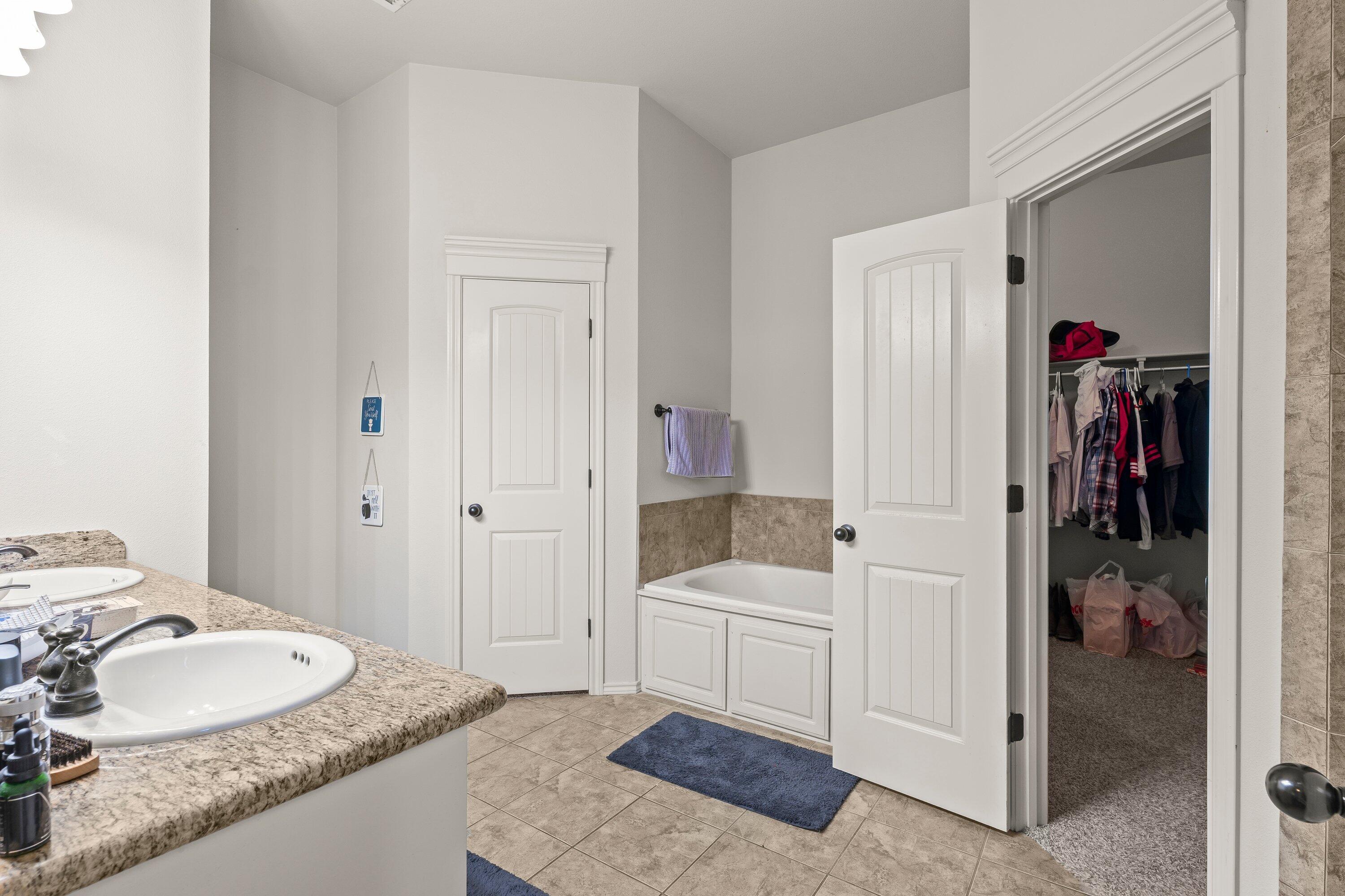6305 93rd Street Lubbock, TX 79424 - Photo 16 of 31 a en suite bathroom with a granite countertop tub and a sink