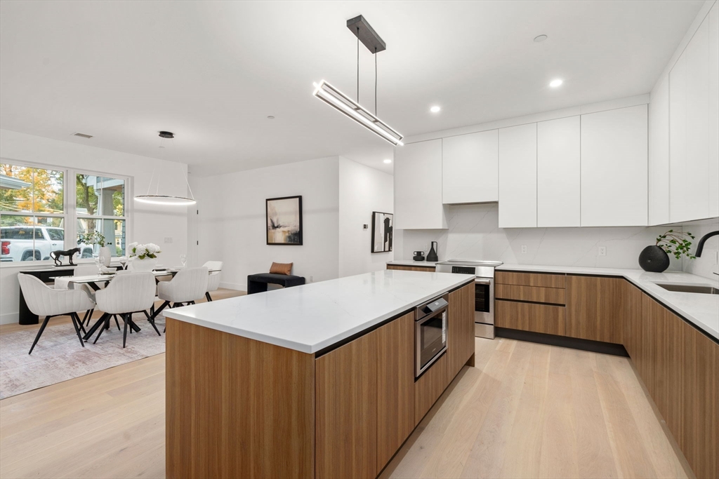 16 Stearns Road, Unit 108 Wellesley, MA 02482 - Photo 14 of 29 a large kitchen with kitchen island a sink a counter space and stainless steel appliances