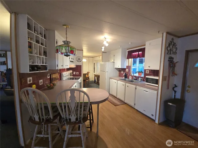 a kitchen with stainless steel appliances a dining table chairs and a refrigerator