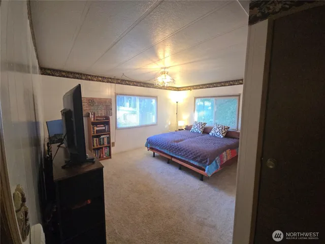 a spacious bedroom with a bed and wooden floor