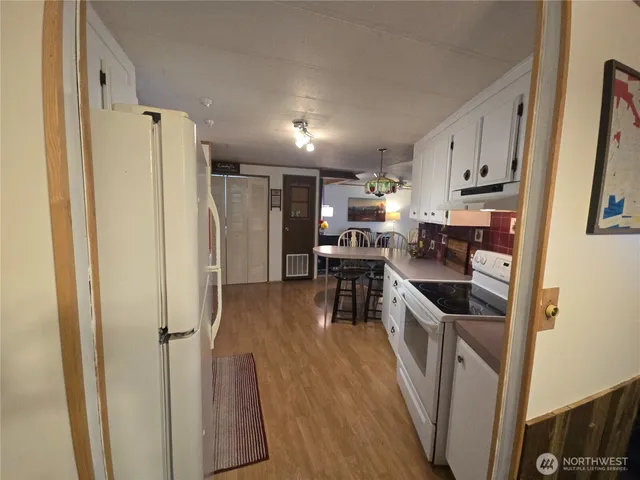 a kitchen with stainless steel appliances granite countertop a refrigerator a stove a sink a stove and a refrigerator with wooden floor