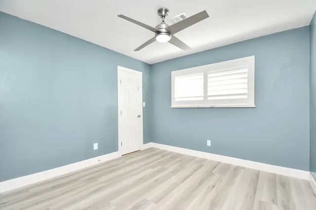 an empty room with windows and fan