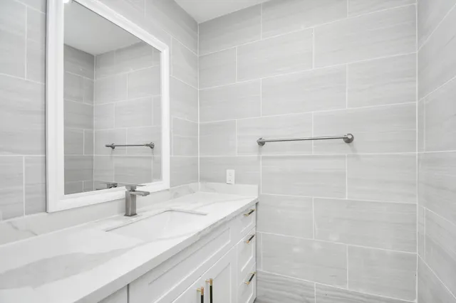 a bathroom with a granite countertop sink and a shower