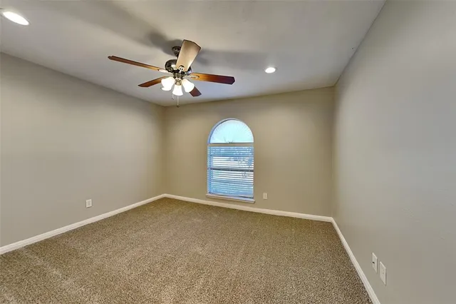 an empty room with windows and ceiling fan