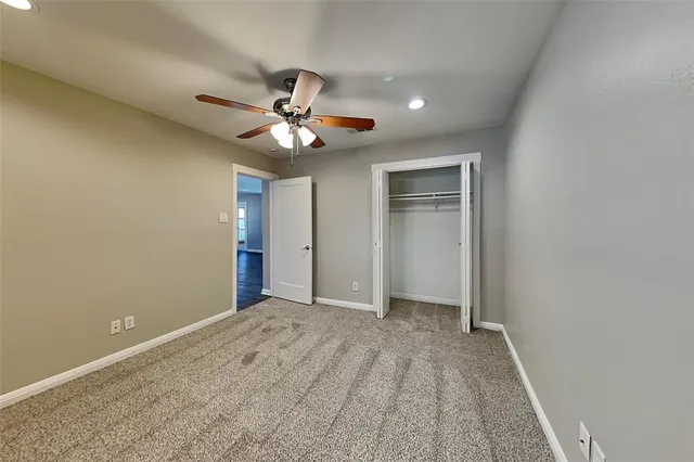 an empty room with a chandelier fan and windows