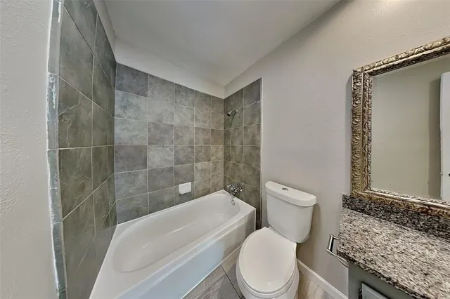 a bathroom with a granite countertop sink a toilet and shower
