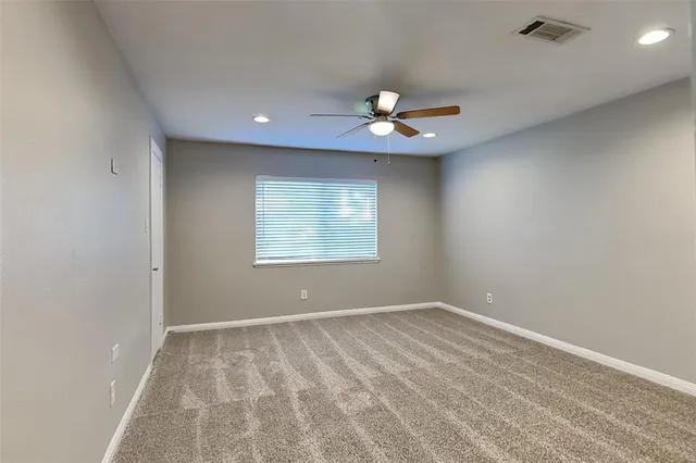an empty room with a ceiling fan and a window
