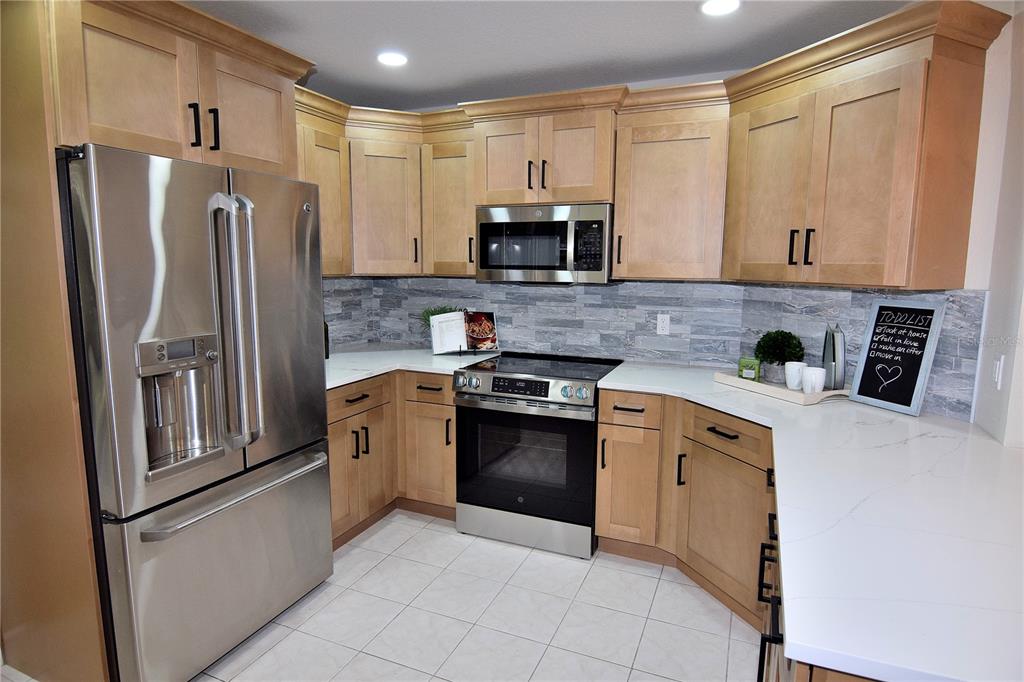 4014 Treetop Circle Spring Hill, FL 34606 - Photo 5 of 31 a kitchen with stainless steel appliances granite countertop a refrigerator sink and stove