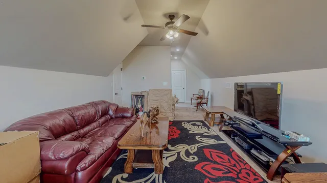 a living room with furniture a flat screen tv and a ceiling fan