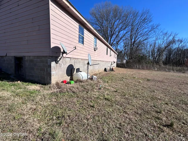 a backyard of a house with wooden fence and a tree