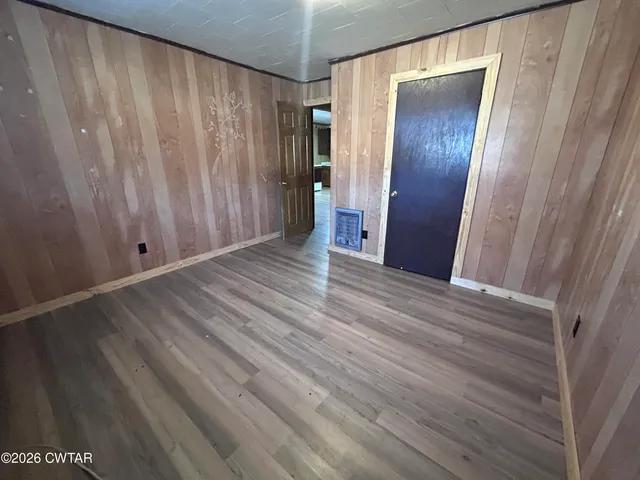 a view of an empty room with wooden floor and entryway