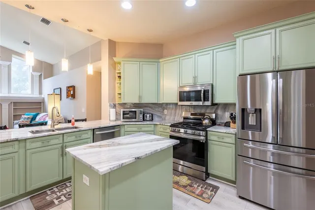 a kitchen with a sink a microwave a refrigerator and cabinets