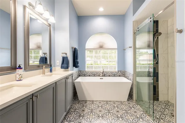 a bathroom with a sink and mirror with bathtub