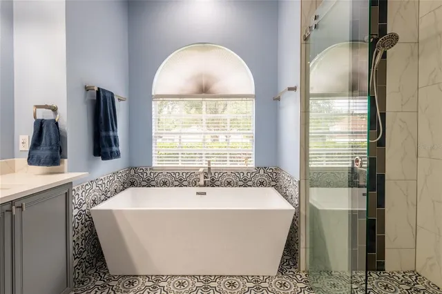a bath tub sitting next to a bathroom sink and a window