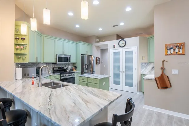 a kitchen with stainless steel appliances kitchen island granite countertop a sink refrigerator dining table and chairs