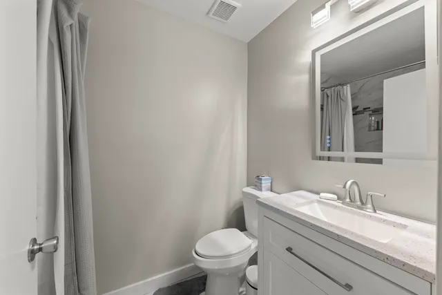a bathroom with a granite countertop toilet sink and mirror