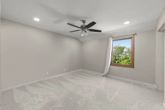 an empty room with windows and fan