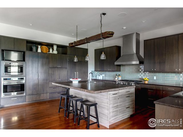 a kitchen with stainless steel appliances granite countertop a sink a stove and a wooden floors