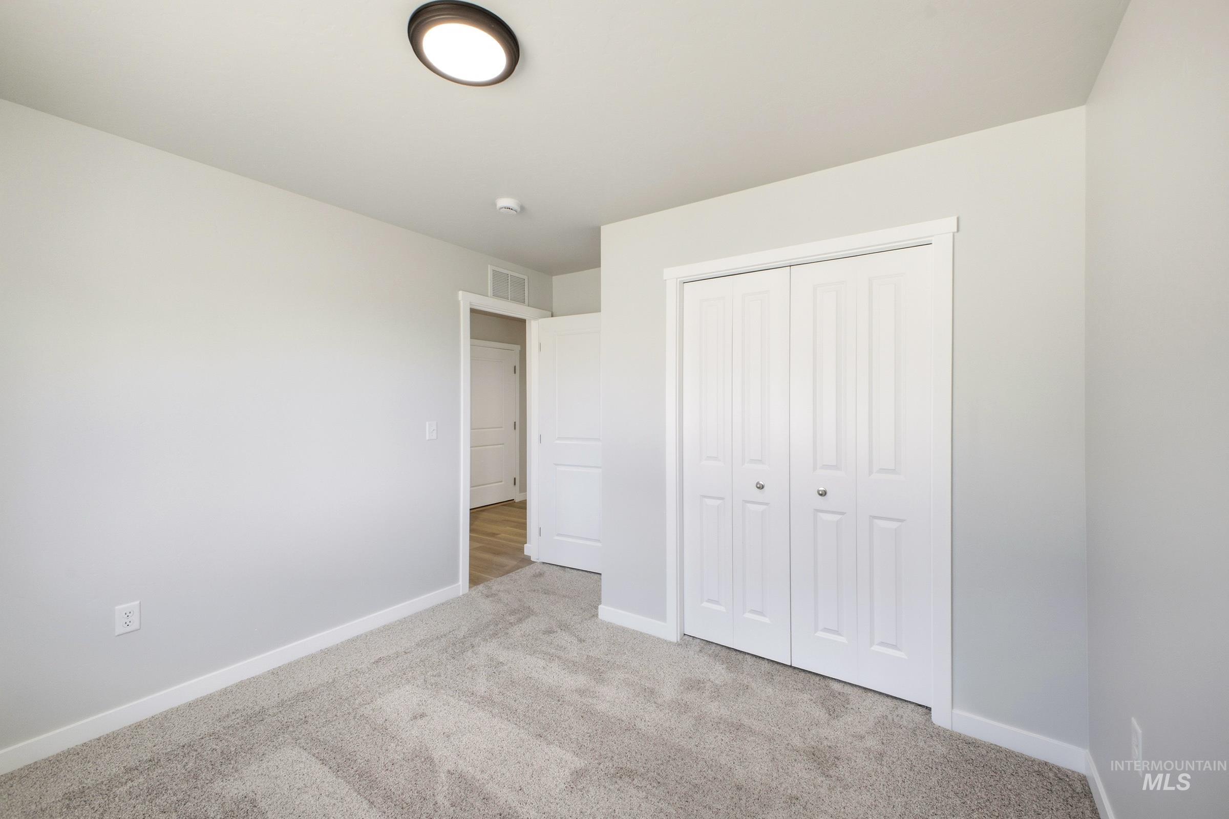 16434 Backfill Avenue Caldwell, ID 83607 - Photo 13 of 19 Plush gray carpeting, white bi-fold closet doors, white trim, and a flush-mount ceiling light