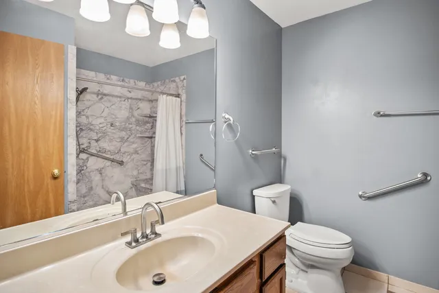 a bathroom with a sink a toilet a mirror and shower curtain