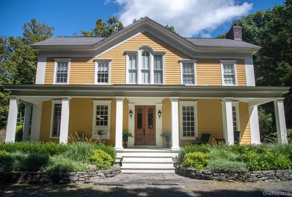 a view of a brick house with large windows and plants