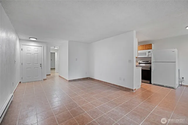 an empty room with a kitchen space and windows