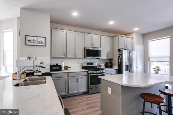 a kitchen with stainless steel appliances a sink a stove a refrigerator cabinets and a window