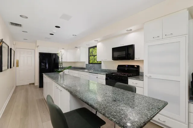 a kitchen with stainless steel appliances granite countertop a sink a stove top oven a counter space and cabinets