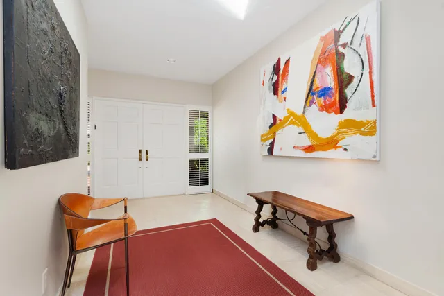 a living room with blue wall paintings a piano and a window