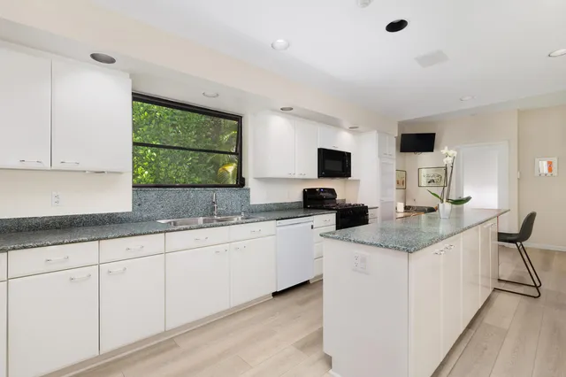 a kitchen with white cabinets and sink