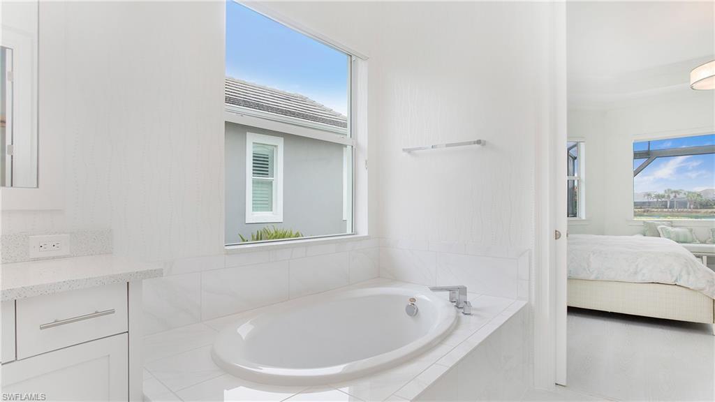 5060 Martinique Drive Naples, FL 34113 - Photo 14 of 38 a bathroom with a tub sink and mirror