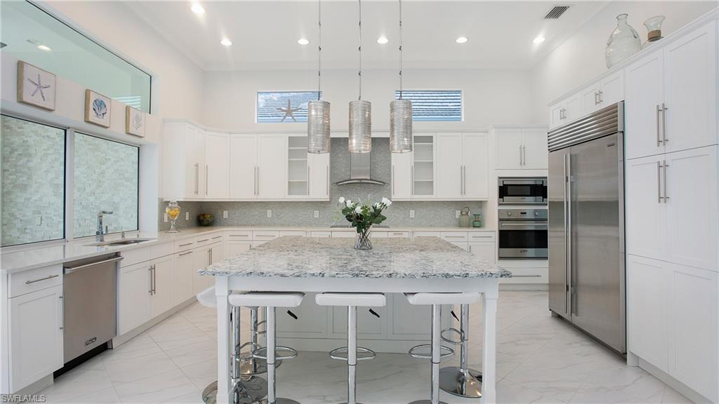 5060 Martinique Drive Naples, FL 34113 - Photo 3 of 38 a kitchen with stainless steel appliances granite countertop a table chairs sink and cabinets