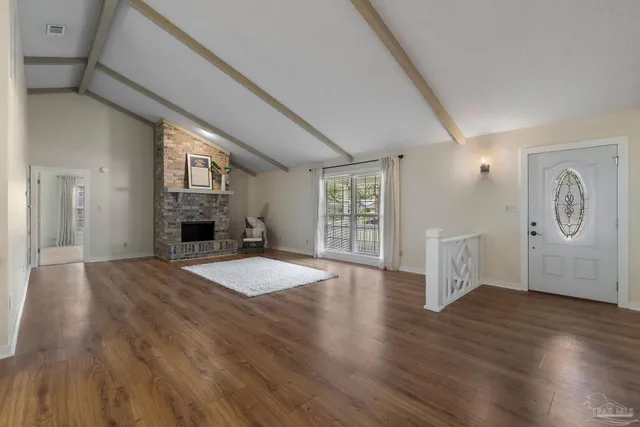 a view of empty room with fireplace and wooden floor