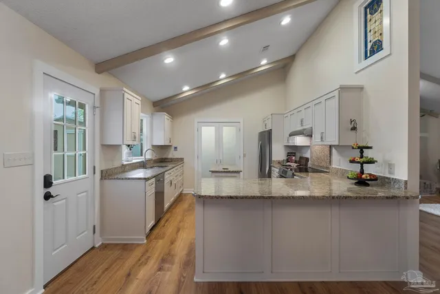 a large kitchen with granite countertop a large counter top appliances and cabinets