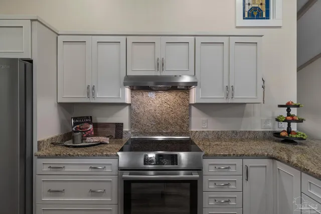 a kitchen with granite countertop white cabinets and stainless steel appliances