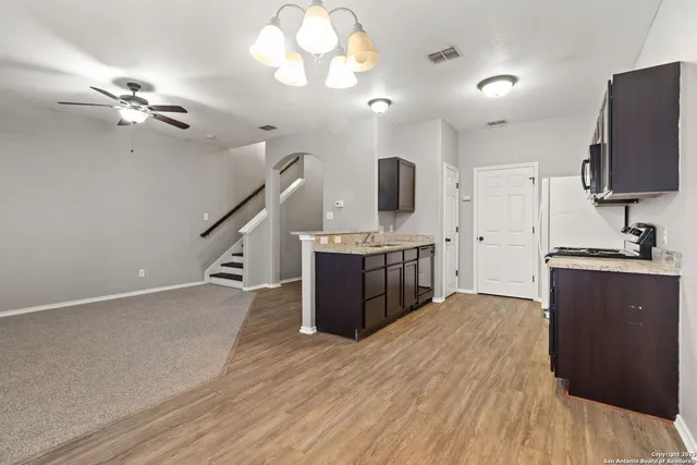 a kitchen with kitchen island stainless steel appliances a sink cabinets and wooden floor