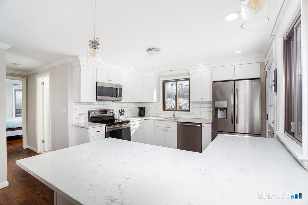 245 Reid Street Fairfield, CT 06824 - Photo 12 of 33 a large kitchen with a refrigerator a stove top oven a sink dishwasher a dining table and chairs with wooden floor